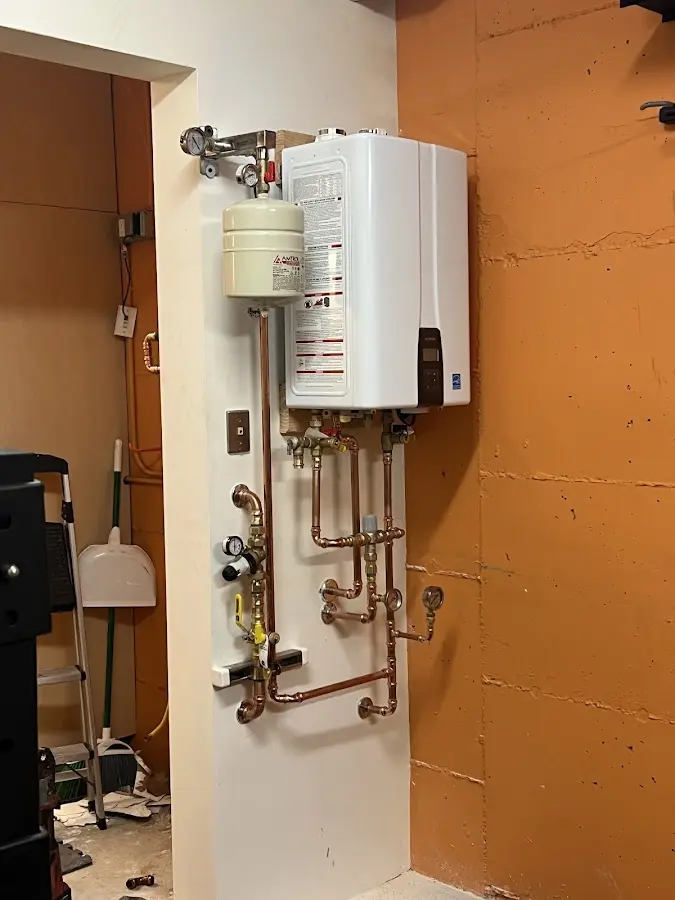 Plumbing technician inspecting water heater connections in Maeser